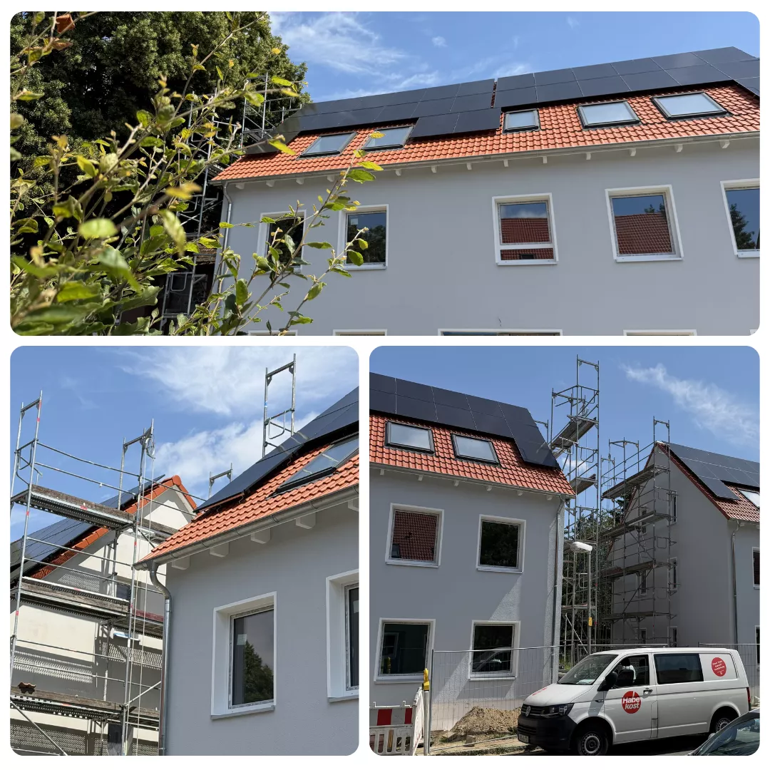 Ein Haus, dessen Dach mit Solarmodulen bedeckt ist, umgeben von Gerüsten; davor steht ein weißer Lkw unter blauem Himmel.