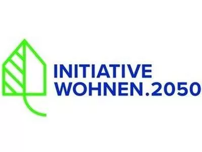 Beyaz zemin üzerinde sağda koyu mavi harflerle INITIATIVE WOHNEN.2050 yazan ev şeklinde yeşil çerçeve.