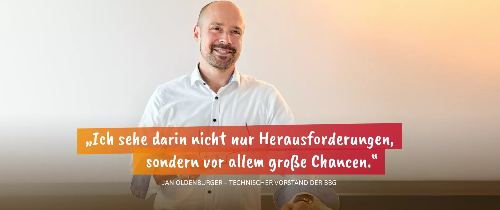 Ein lächelnder Mann steht vor einem einfachen Hintergrund mit einem deutschen Zitat und dem Namen Jan Oldenburger auf dem Bild.
