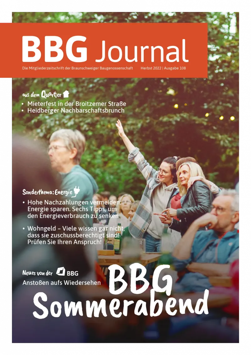 Eine Gruppe von Menschen genießt ein Treffen im Freien, hebt Gläser und lächelt, mit festlicher Dekoration im Hintergrund.