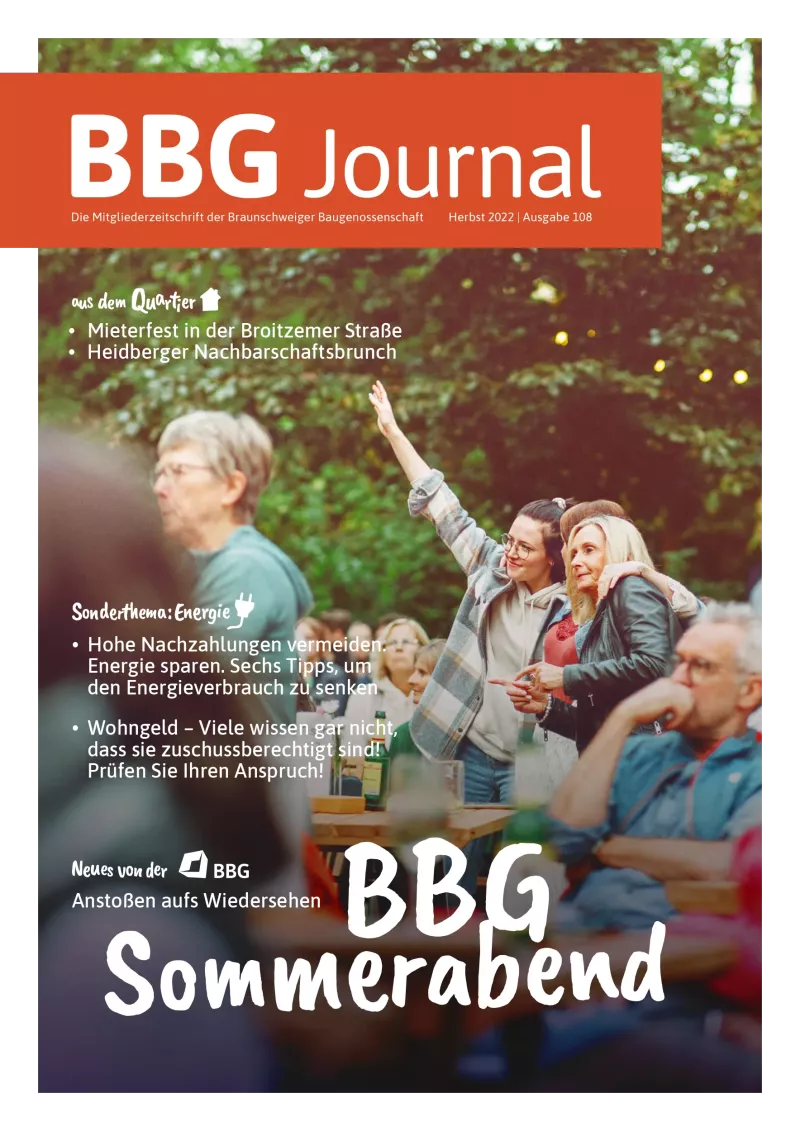 Eine Gruppe von Menschen genießt ein Treffen im Freien, hebt Gläser und lächelt, mit festlicher Dekoration im Hintergrund.