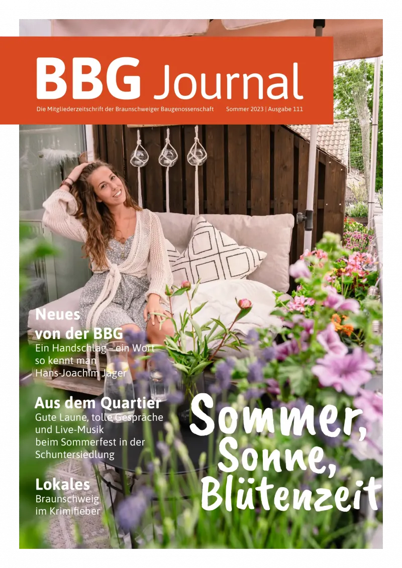 Eine lächelnde Frau in einem weißen Kleid sitzt auf einem gemütlichen Sofa im Freien, umgeben von Kissen und Pflanzen, mit einem Text-Overlay aus einer Sommerzeitschrift.