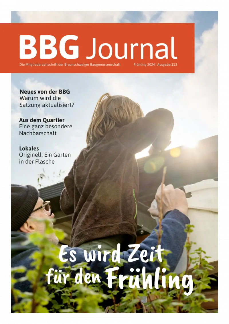 Ein Kind auf der Schulter eines Erwachsenen streckt sich der Sonne entgegen, die Menschen um es herum lächeln unter einem klaren Himmel.