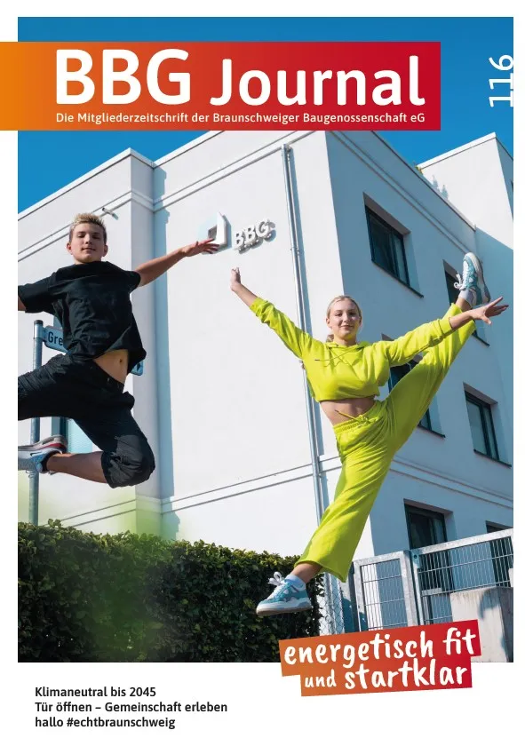 Zwei fröhlich gekleidete Menschen springen vor einem modernen weißen Gebäude mit den Buchstaben BBG an der Wand in die Luft.