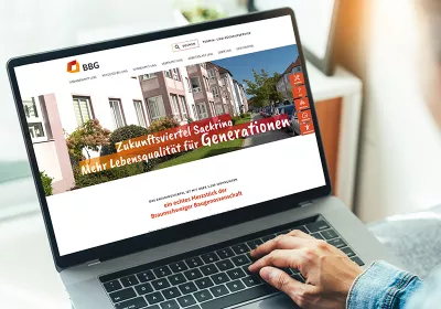 Eine Person, die einen Laptop benutzt, zeigt eine Wohnungs-Website mit einem deutschen Text über Lebensqualität für Generationen an.