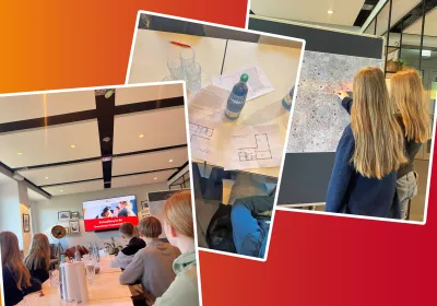 Eine Gruppe von Schülern in einem Klassenzimmer, Papiere und Wasserflaschen auf den Tischen, zwei Personen, die auf eine Karte an der Tafel zeigen.