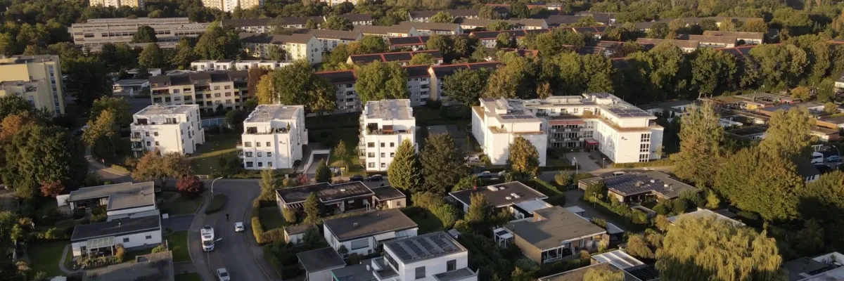 Aerial view of a suburban neighborhood with modern houses, trees and streets under a clear sky.