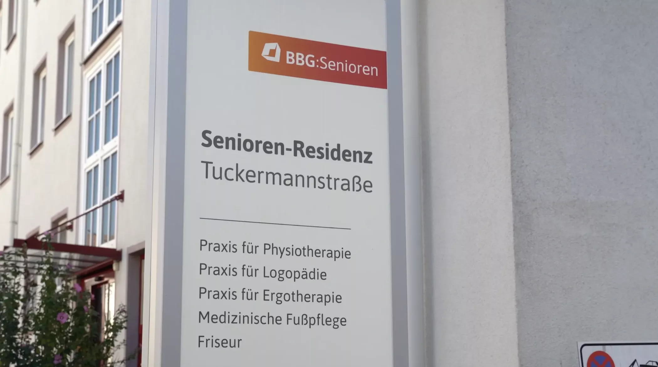 Senioren-Residenz Tuckermannstraße'deki bir tabela, fizyoterapi ve ayak bakımı da dahil olmak üzere mevcut tıbbi ve terapötik hizmetleri Almanca olarak göstermektedir.