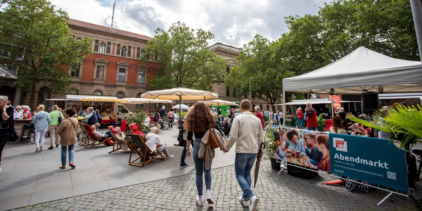 The town square, surrounded by trees and historic buildings, is home to a lively market with food stalls, tents and open-air seating.