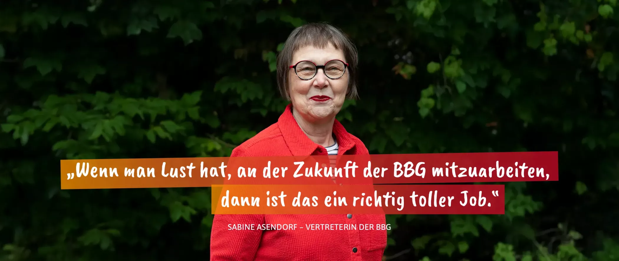 Older woman with short brown hair and a red coat stands in front of green bushes and smiles, quote about working at BBG.